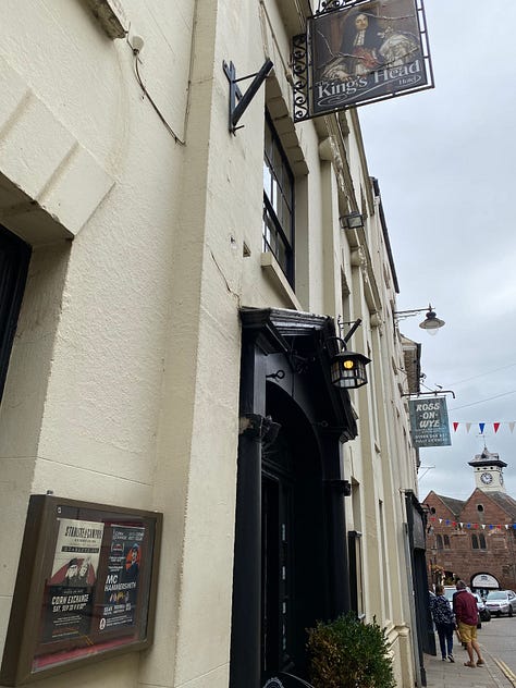 The KIngs Head hotel with people smiling outside and working on a laptop inside the bar