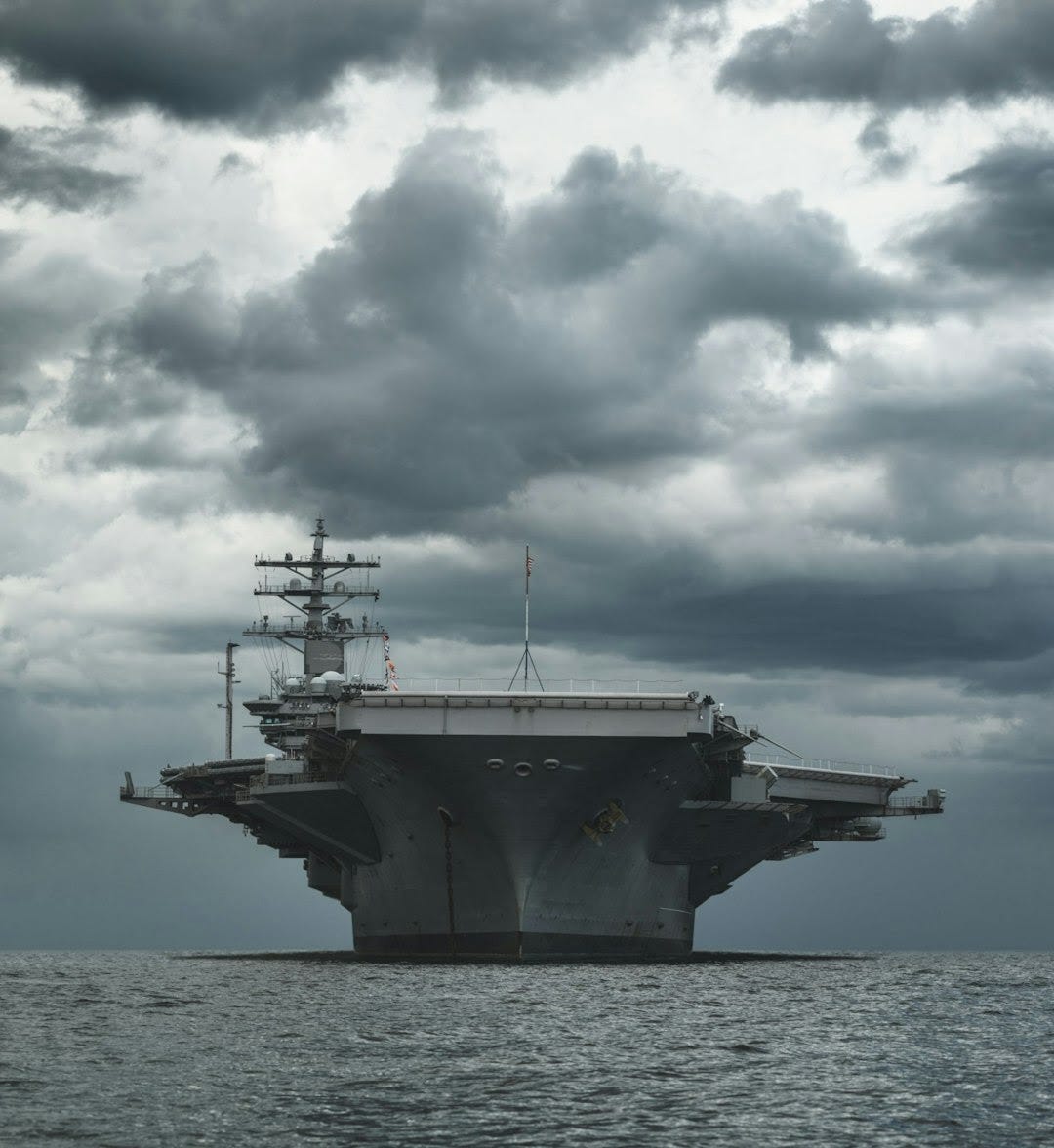 a large aircraft carrier floating on top of a body of water a large aircraft carrier floating on top of a body of water