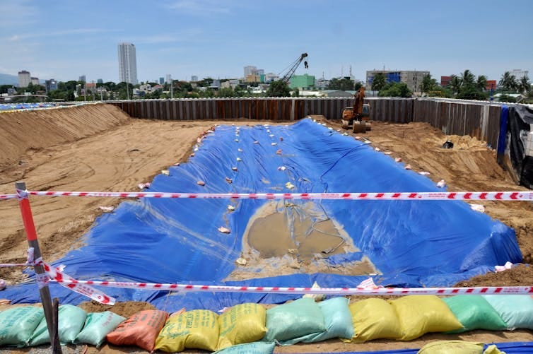 A pit with sandbags and tarps and buildings in the background. A pit with sandbags and tarps and buildings in the background.