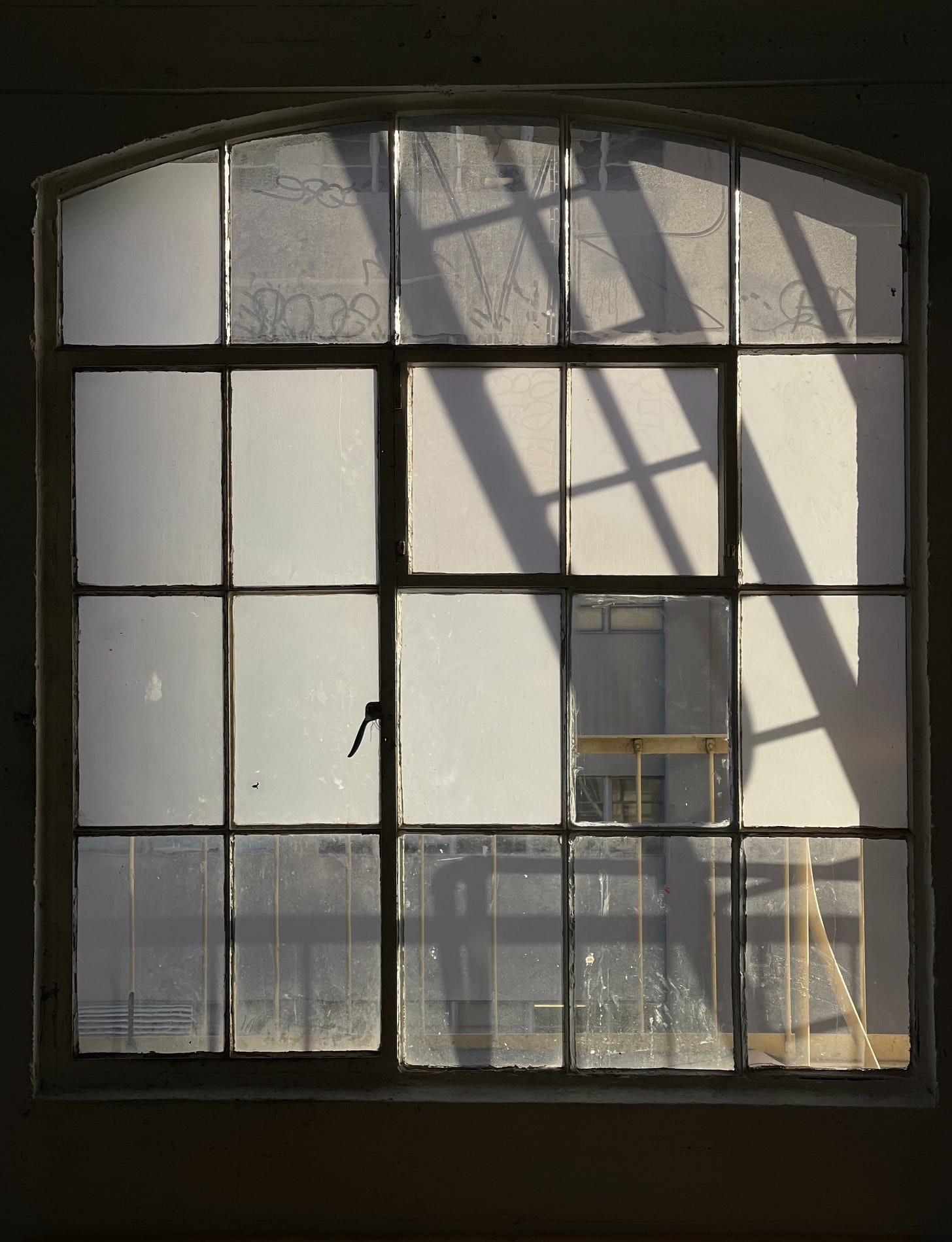 Shadow of a fire escape through a large, paned window. Shadow of a fire escape through a large, paned window.