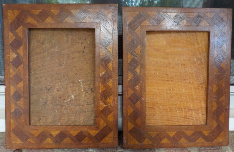 May include: Two wooden picture frames with a decorative geometric pattern around the edges. The frames are made of light and dark brown wood and are both empty.
