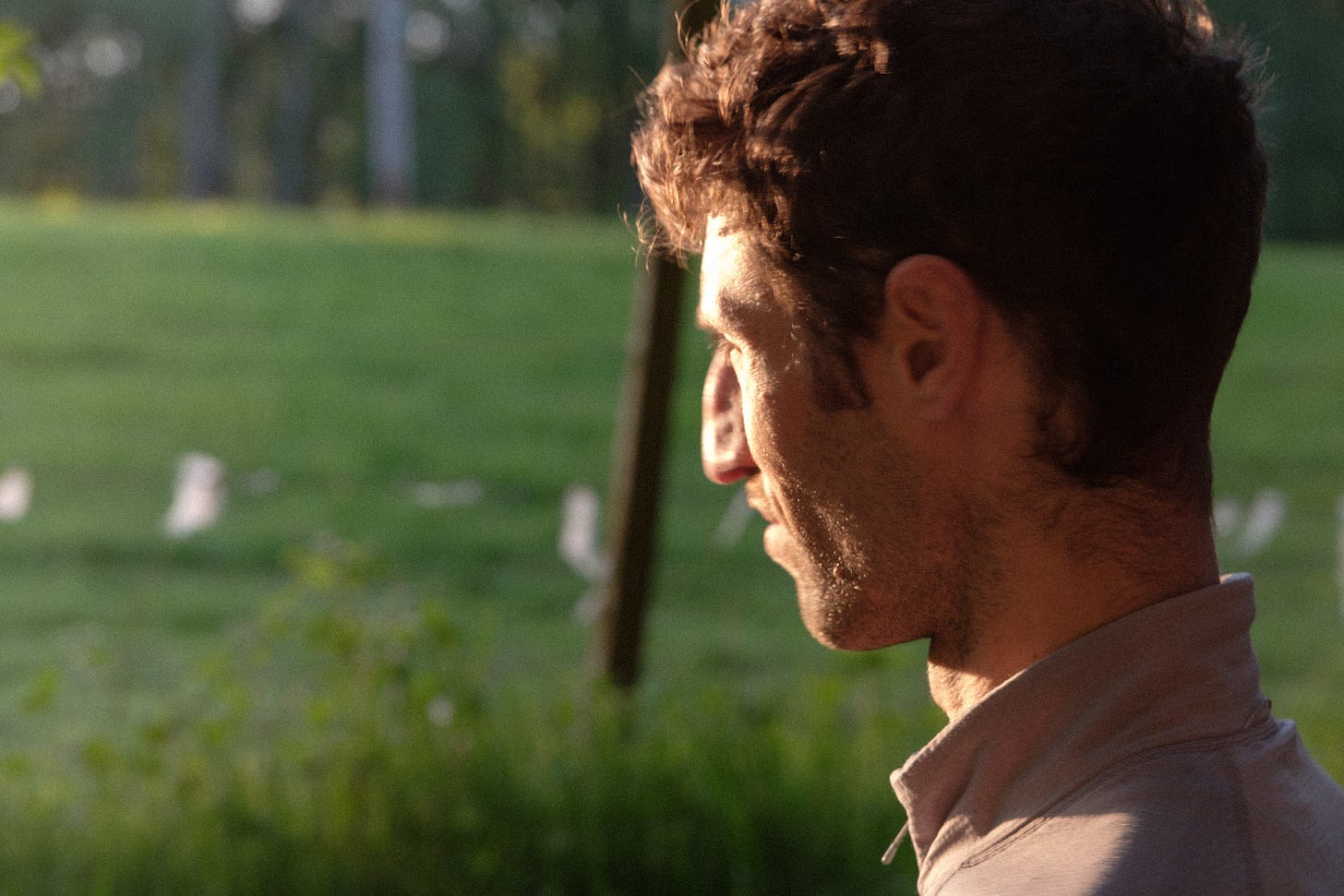 A backlit image of the author at sunset, gazing into the golden sun with eyes partially closed. The light is soft and warm, casting long shadows and creating a thoughtful, dreamlike atmosphere.
