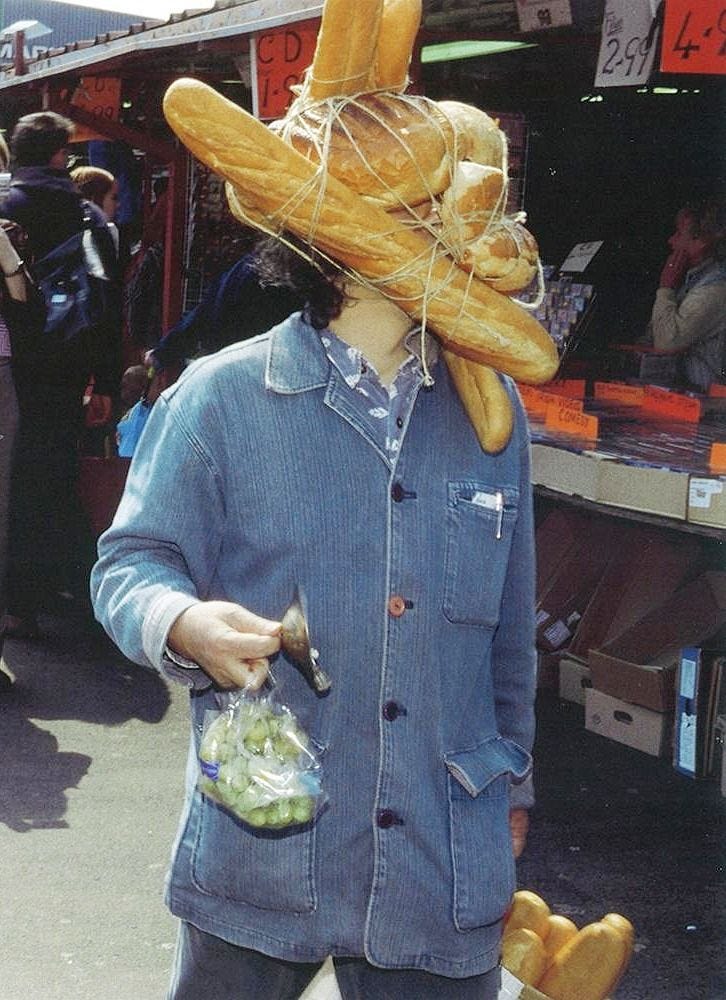 This may contain: a person wearing a hat made out of bread on their head and holding a bag