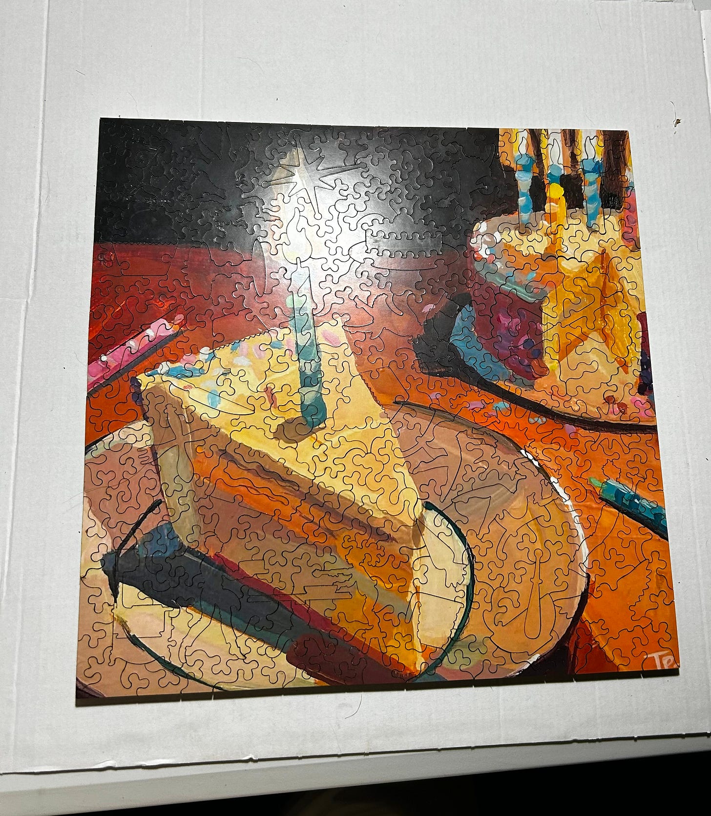 A multicolored slice of cake, shining candle on the slice,  and the cake without the slice and a few more candles on top. It is a jigsaw puzzle with lots of tiny pieces, some of people, some of things and some just abstract!