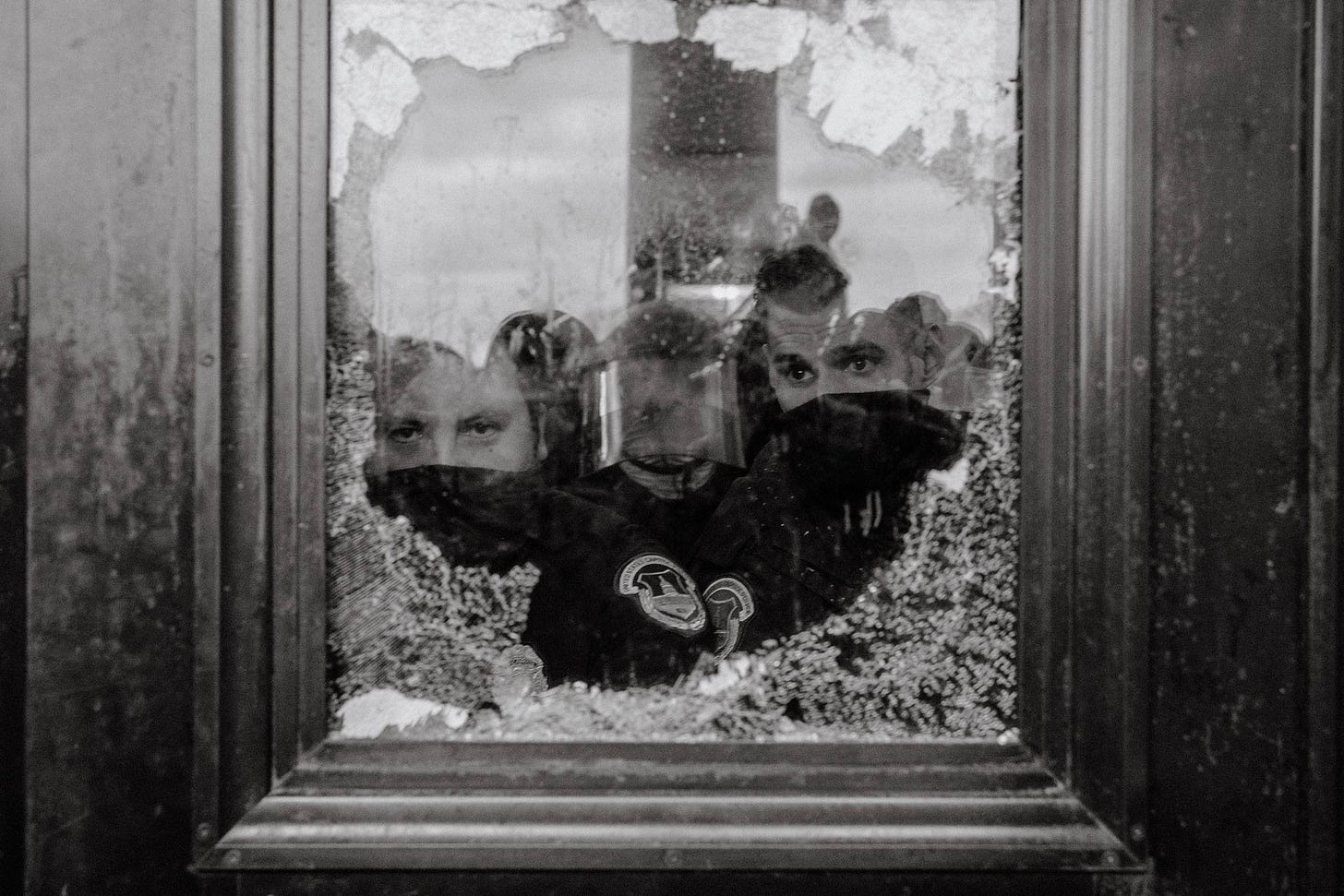 U.S. Capitol Police officers watch a mob of supporters for President Donald Trump through a partially broken window of the U.S. Capitol Building in Washington on Jan. 6, 2021.