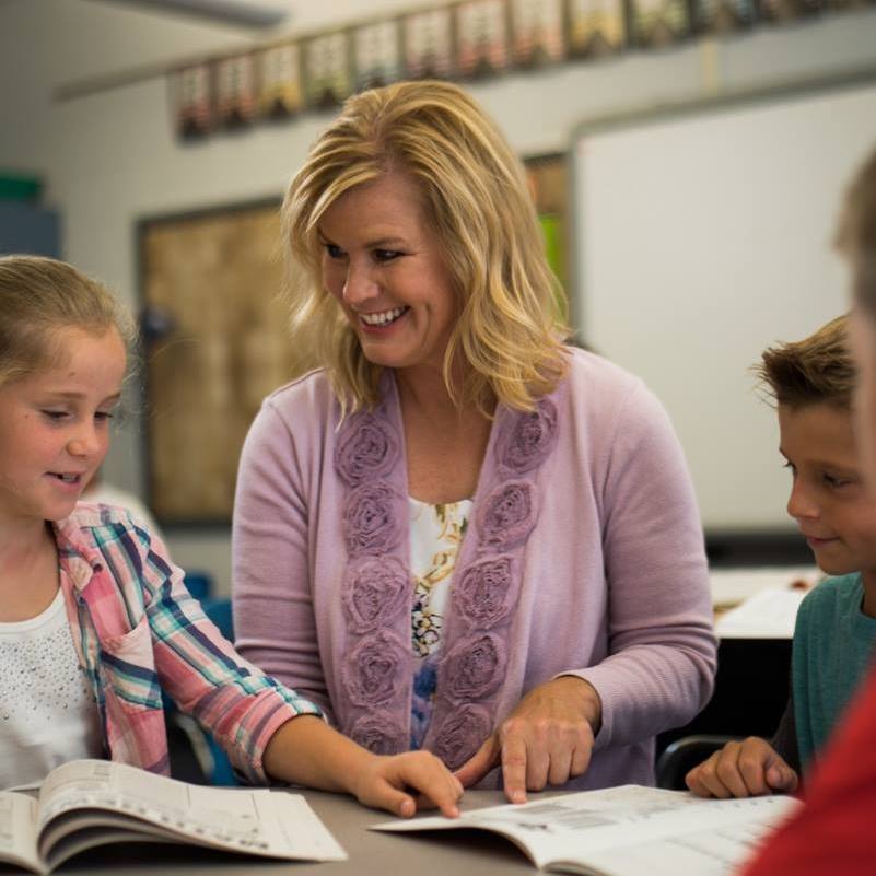 A person and children looking at a book

Description automatically generated