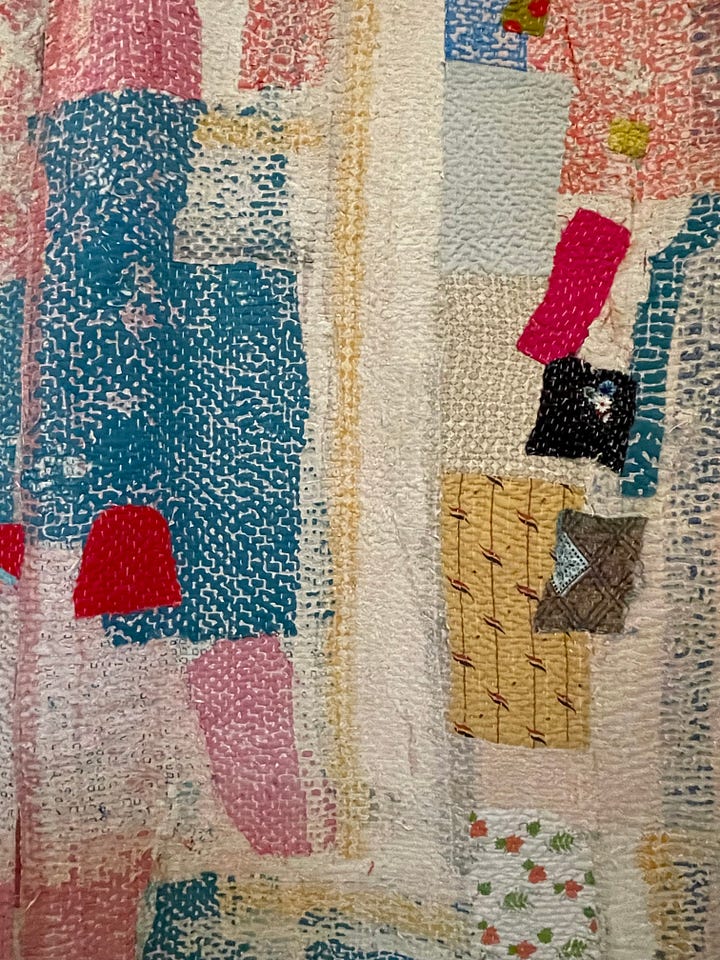 A mostly pink and blue quilt with red and yellow accents.