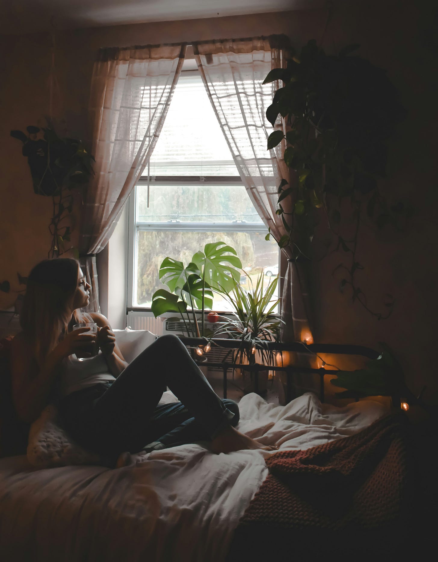 a-woman-sitting-on-a-bed-in-front-of-a-window