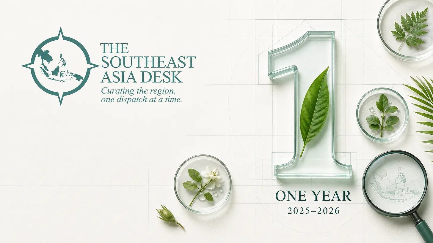 A graphic celebrating "One Year" (2025–2026) for The Southeast Asia Desk, featuring the publication's logo, a glass number one with a green leaf inside, petri dishes with local botanical specimens, and a magnifying glass over a map of Southeast Asia.