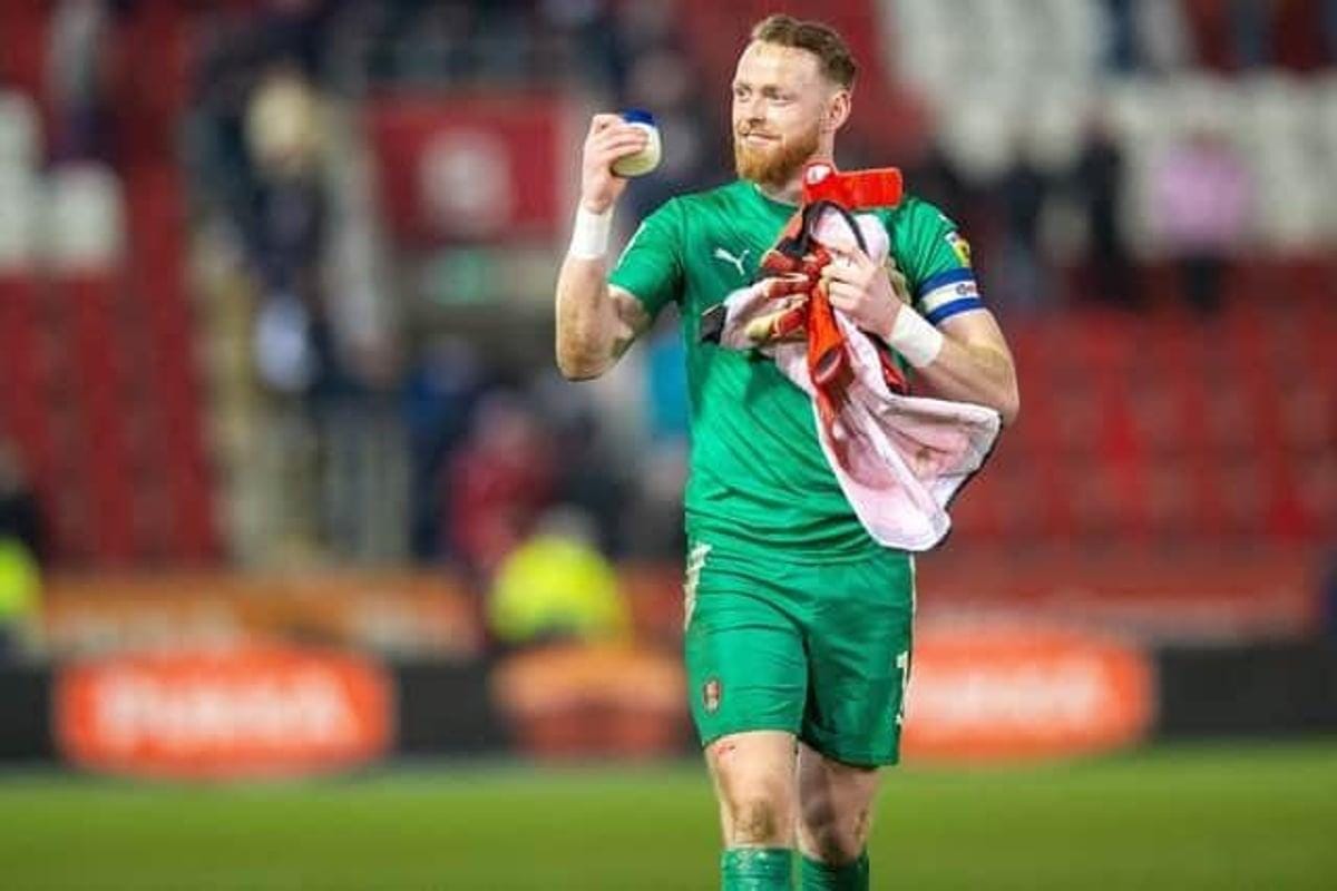 A person in a green uniform holding a towel

Description automatically generated