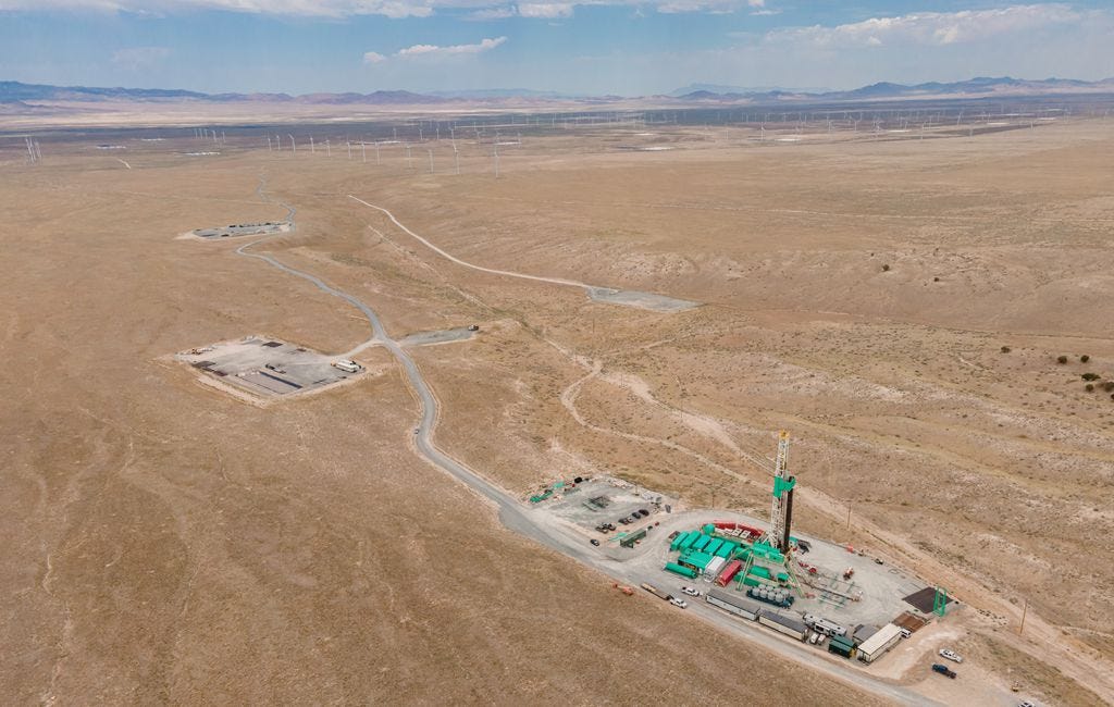 (Eric Larson | FlashPoint SLC) The buildings and drill rig of the Utah FORGE project stand out from the desert floor near Milford, Utah. In the background are some of Beaver County's power-generating windmills.