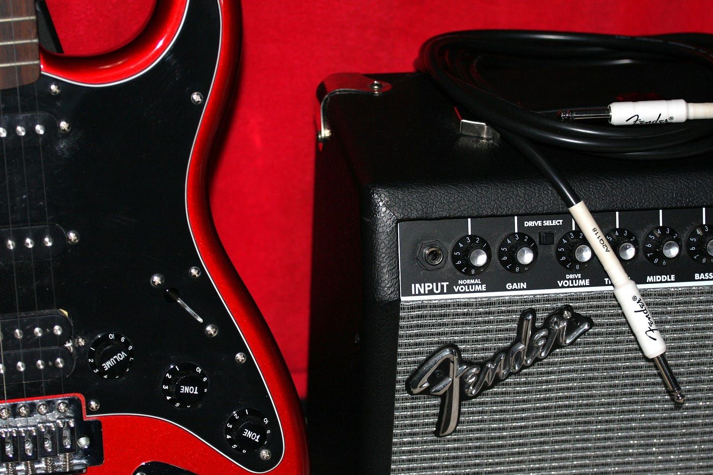 Black electric guitar with red trim next to amplifier Black electric guitar with red trim next to amplifier