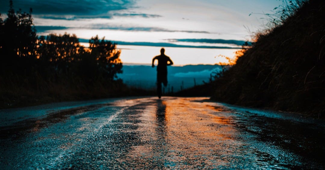 silhouette photo of a person running on road