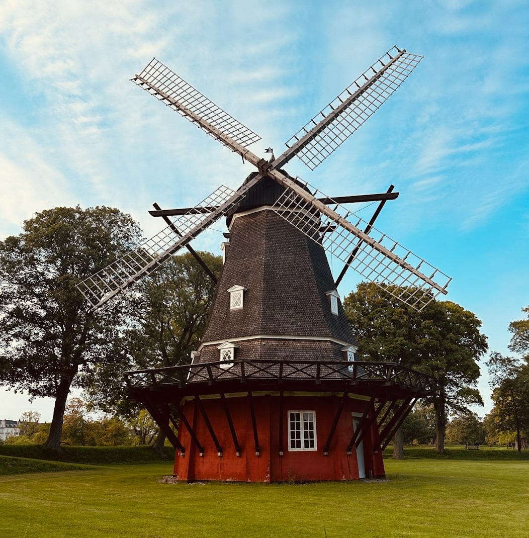 a windmill sitting on top of a lush green field a windmill sitting on top of a lush green field