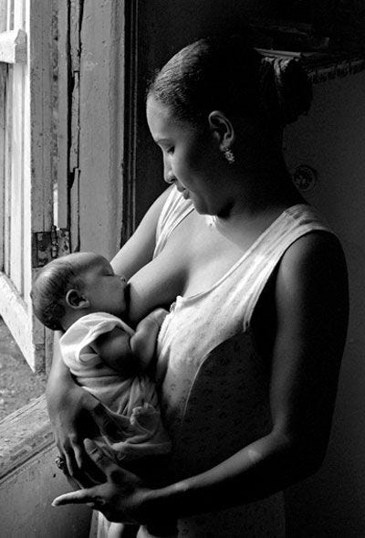 This may contain: a woman holding a baby in her arms