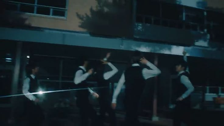 This may contain: several people standing in front of a building at night