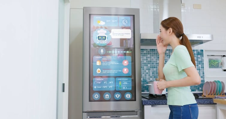 Woman with a ponytail looking at a refrigerator door that shows icons and widgets Woman with a ponytail looking at a refrigerator door that shows icons and widgets