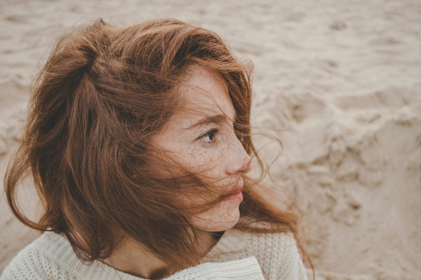 Woman on beach looking away red hair