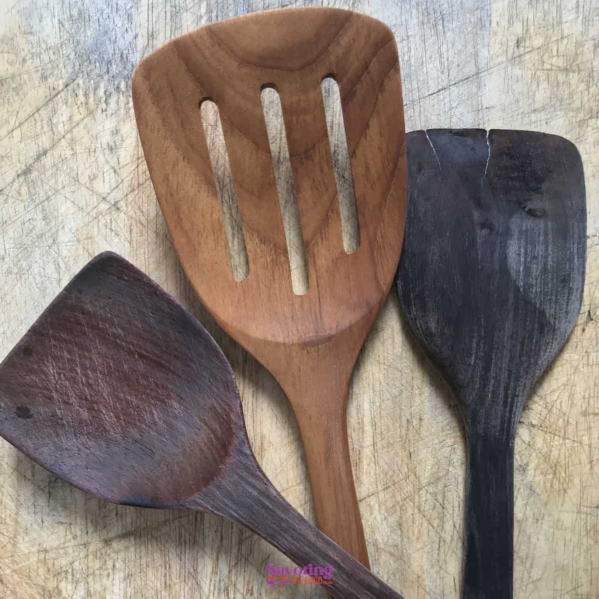 Three wooden kitchen utensils on a wooden table.