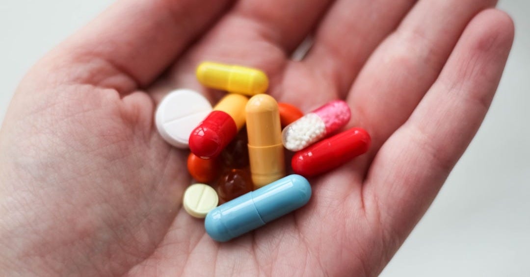 orange and white medication pill on persons hand