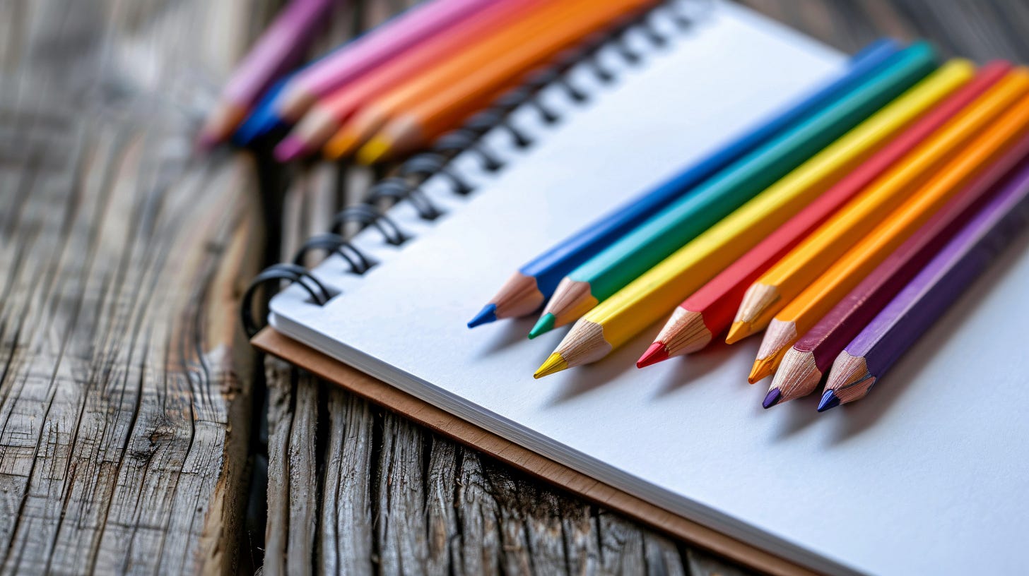Blank notebook and a bunch of colorful pencils over a wooden table.