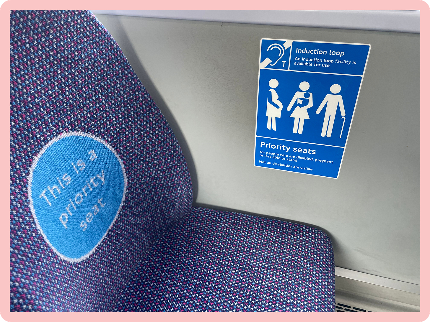 A photo of a seat on a bus, which features a big round circle in the seat cushion which reads 'This is a priority seat.' To its right, on the wall of the bus, a blue sign reads 'Priority seat for those who are pregnant, disabled or less able to stand." A photo of a seat on a bus, which features a big round circle in the seat cushion which reads 'This is a priority seat.' To its right, on the wall of the bus, a blue sign reads 'Priority seat for those who are pregnant, disabled or less able to stand."