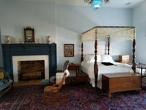 The Dickson Williams Mansion, a brick building with a white porch; the parlor, showing a round table surrounded by black chairs on a red oriental rug in front of a fireplace; the kitchen area, showing original north carolina furniture; bedrooms of the house, along with a portrait of General John Hunt Morgan sitting in a chair in a black coat with tall black boots; and the bed where he spent his last night.