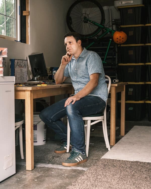 Sean Wittmeyer sitting at a wooden table in the office garage at his home.