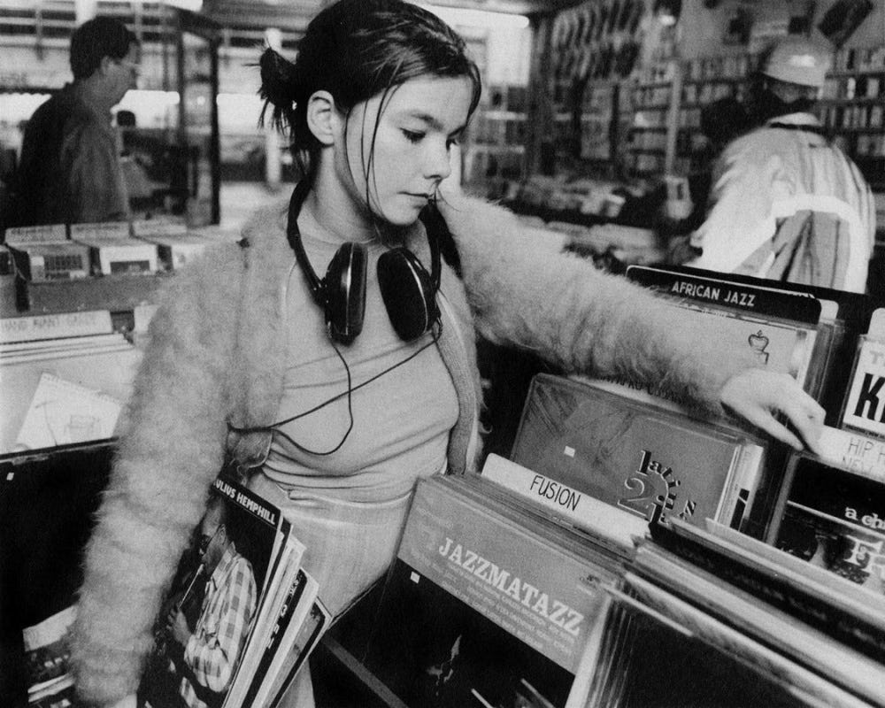 Björk with headphones around her neck, carrying a stack of records under her arm, which includes Julius Hemphill and Oliver Lake's Buster Bee