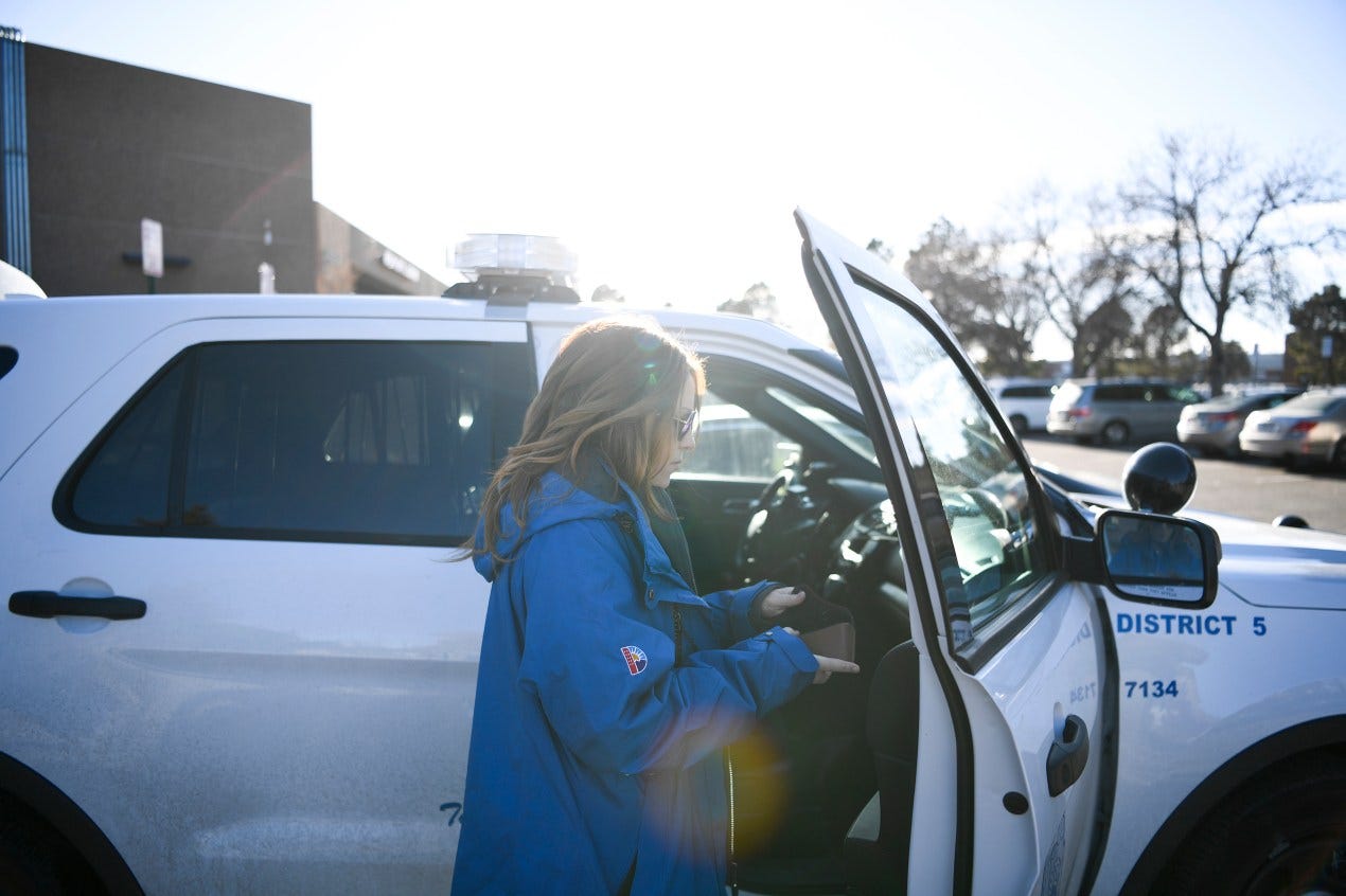 A woman wearing sunglasses and a blue jacket gets into a white police sport utility vehicle A woman wearing sunglasses and a blue jacket gets into a white police sport utility vehicle