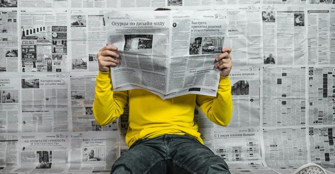a person sitting on the floor reading a newspaper a person sitting on the floor reading a newspaper