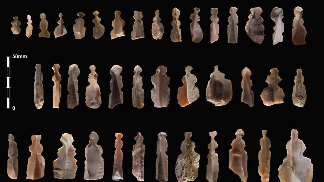 40 flint figures resembling little women in dresses, lined up in three horizontal rows. They are beautiful shades of white, topaz and mauve