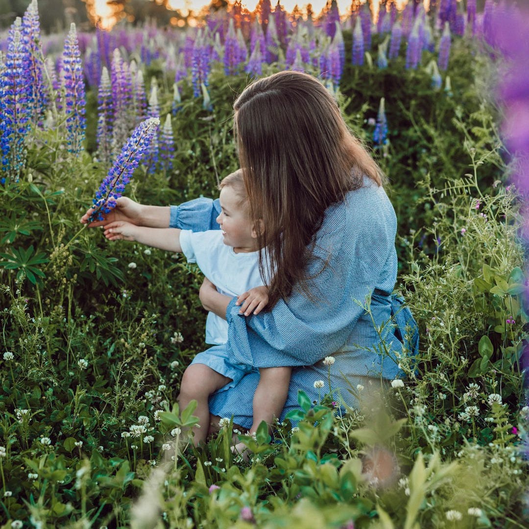 woman sitting with baby on her lap surrounded with purples flower woman sitting with baby on her lap surrounded with purples flower