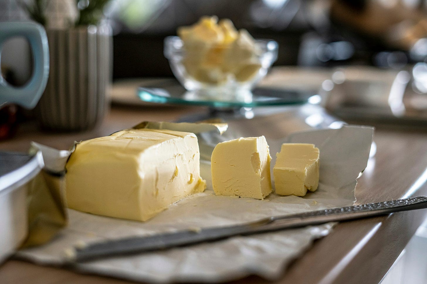 A big block of butter, cut into cubes, with a butter knife resting nearby.