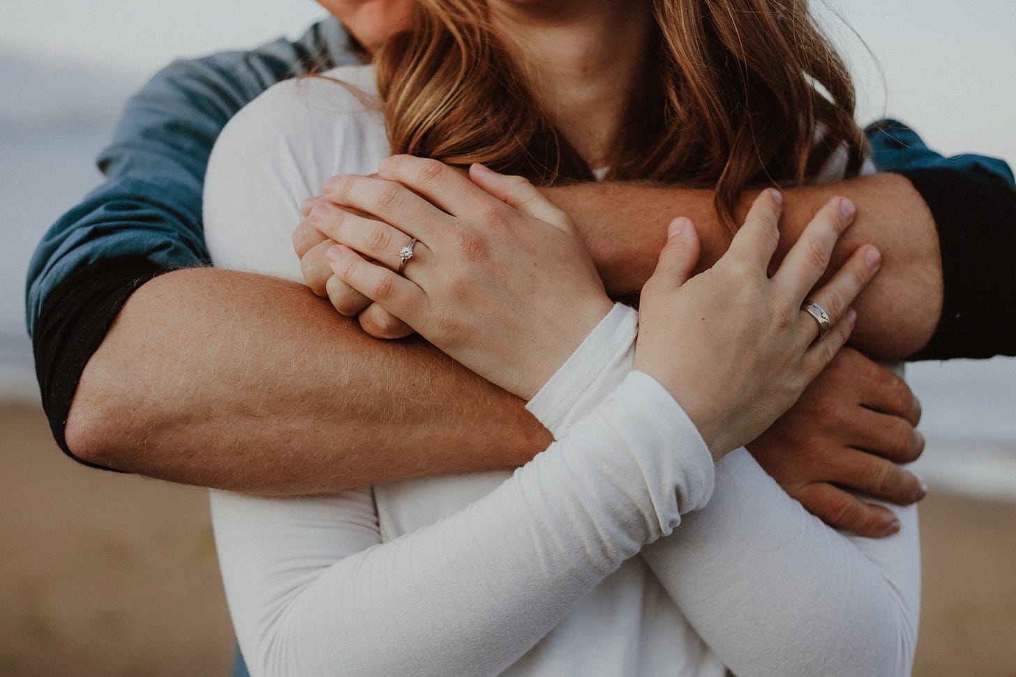 A couple holds one another on a beach.