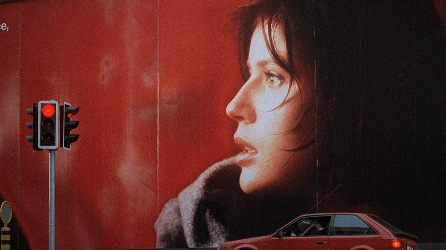 Three Colors: Red | Still features Irène Jacob across a poster covering a building, in red. Three Colors: Red | Still features Irène Jacob across a poster covering a building, in red.