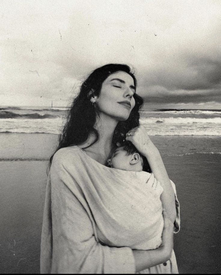 This may contain: a woman holding a baby on the beach