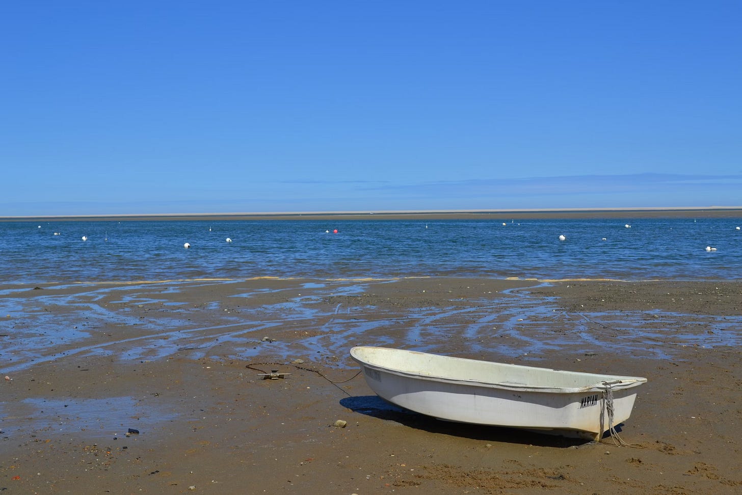 White boat sitting on top of a sandy beach on Cape Cod, Massachusetts.