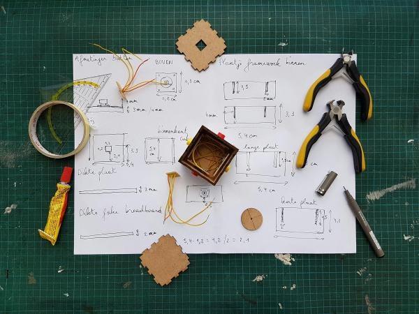 Tools, glue and piece of a prototyped box on a sheet of paper with drawing and dimensions Tools, glue and piece of a prototyped box on a sheet of paper with drawing and dimensions