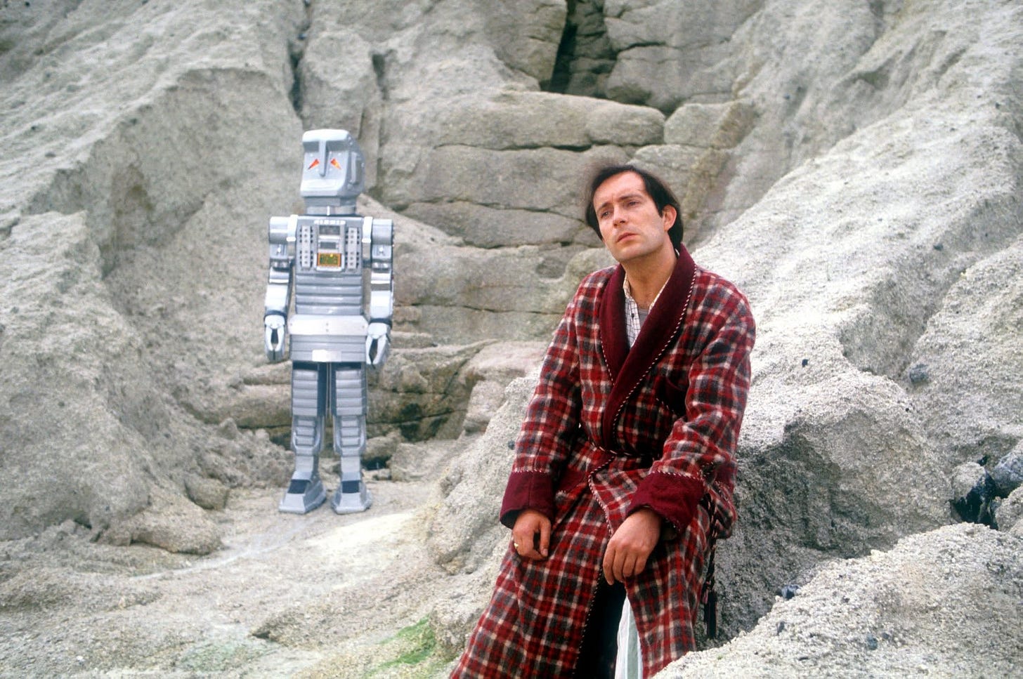 Arthur Dent in his dressing gown beside Marvin the Paranoid Android on the rocky surface of Magrathea. Arthur Dent in his dressing gown beside Marvin the Paranoid Android on the rocky surface of Magrathea.
