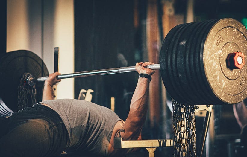 man performing a heavy eccentric focused barbell bench press. man performing a heavy eccentric focused barbell bench press.