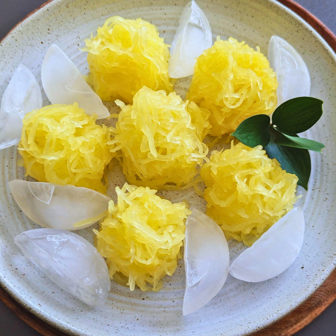 Chilled mounds of spaghetti squash arranged on a serving platter surrounded by ice cubes, styled to resemble Japanese somen noodles.
