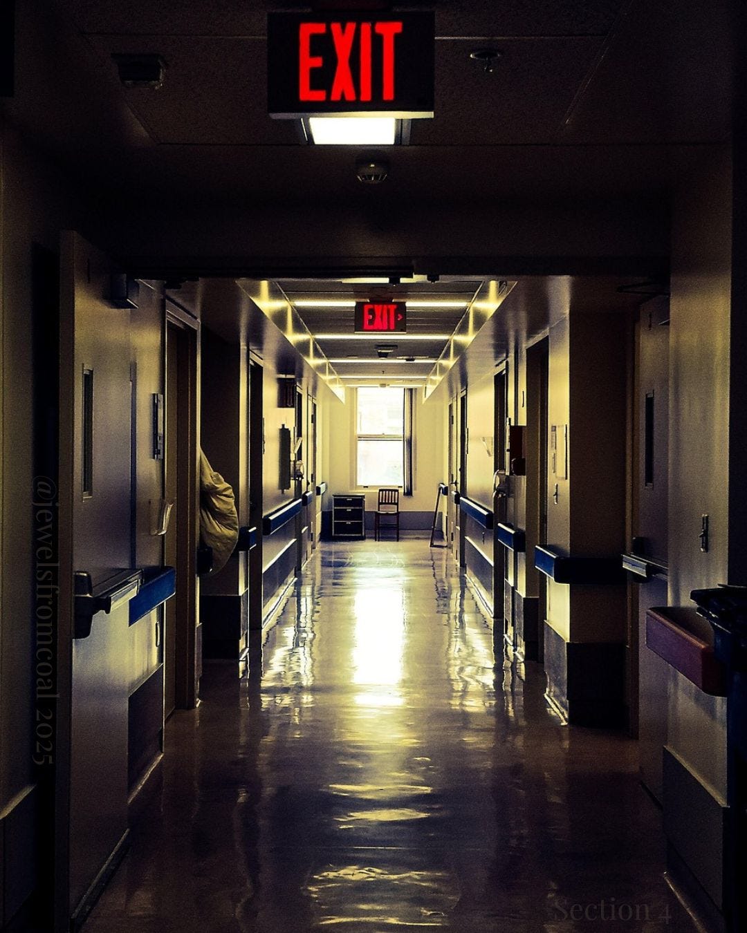 A dimly lit hospital hallway with reflective floors and two illuminated red EXIT signs. The corridor is empty and quiet, evoking isolation and the absence of care.