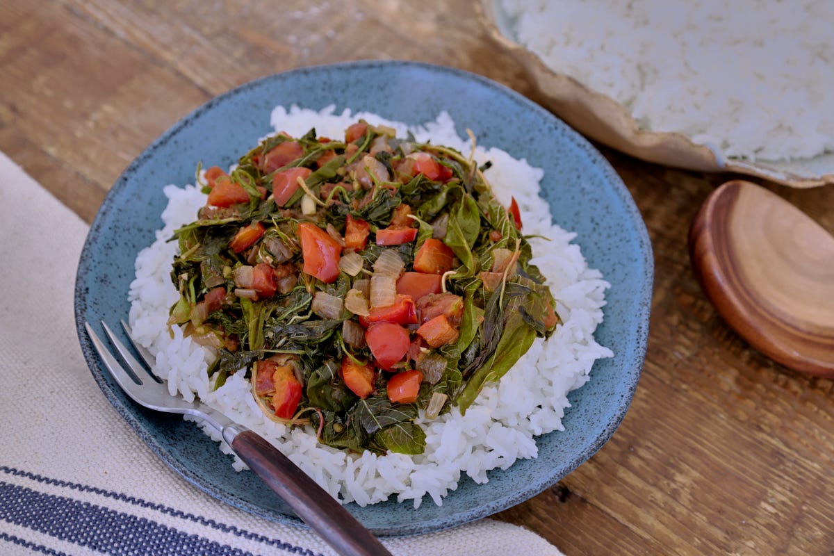 amaranth greens over rice on a plate with a fork, a bowl of rice, wooden spoon, and kitchen towel amaranth greens over rice on a plate with a fork, a bowl of rice, wooden spoon, and kitchen towel