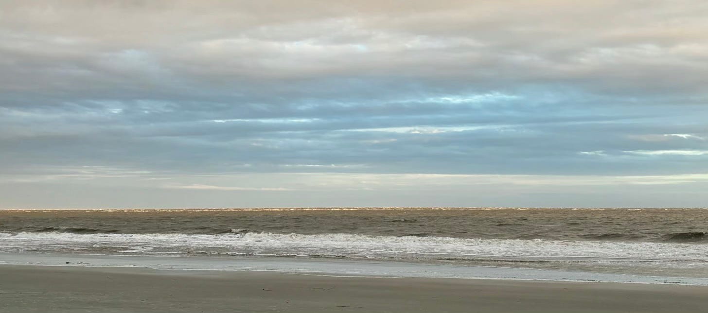 ocean beach under blue and grey cloudy sky