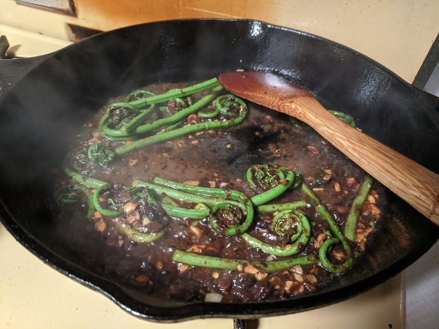 a cast iron of fiddlehead ferns in fermented black bean sauce