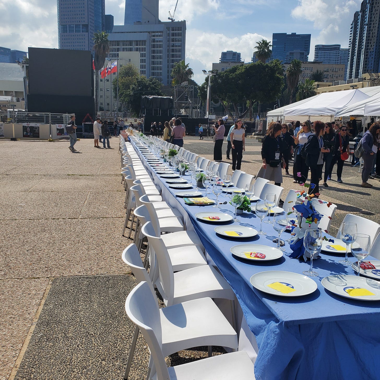 A long table set for Shabbat dinner with plates and drinking glasses. 