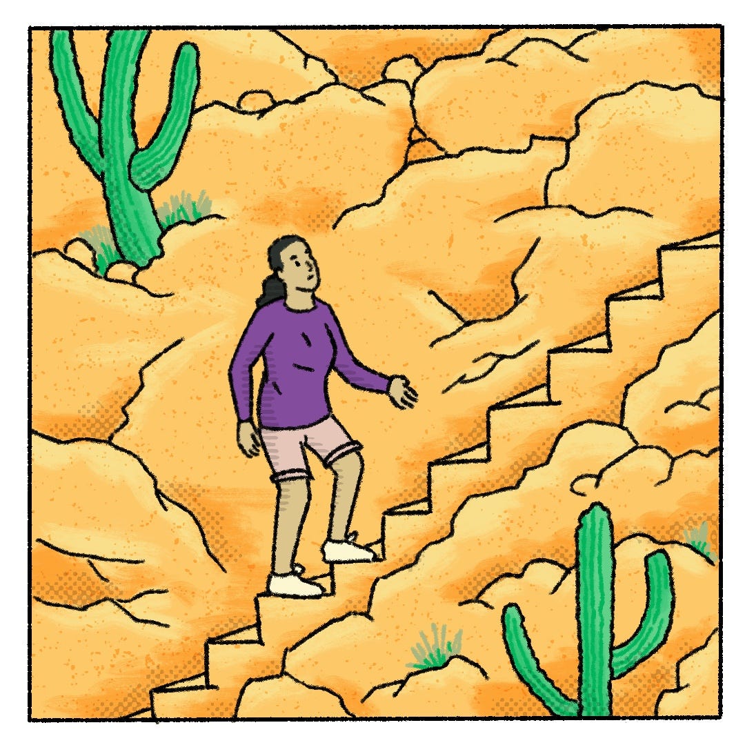 a woman wearing shorts and long sleeves walks up a stone staircase amongst rocks and tall cacti.