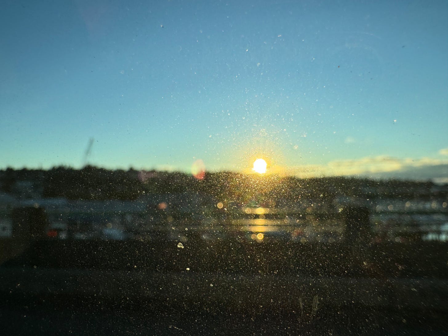 Photo of a sunrise (or sunset) through a dirty window — sunlight breaking through the smudges, blurry but beautiful.
