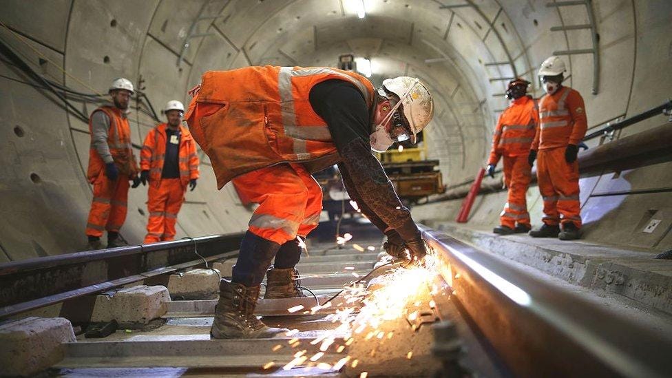 Construction workers wearing white hard hats and orange hi-viz protective clothing work inside a tunnel for the Elizabeth Line underground line on 16 November, 2016. Construction workers wearing white hard hats and orange hi-viz protective clothing work inside a tunnel for the Elizabeth Line underground line on 16 November, 2016.